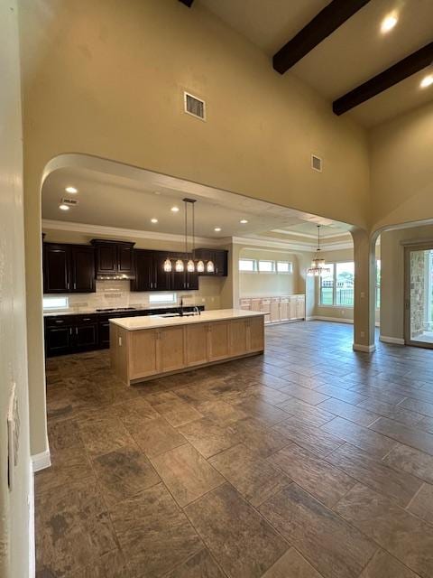 201 Grand Oaks Ln, Georgetown, TX 78628 - kitchen featuring a towering ceiling, arched walkways, open floor plan, light countertops, and beamed ceiling