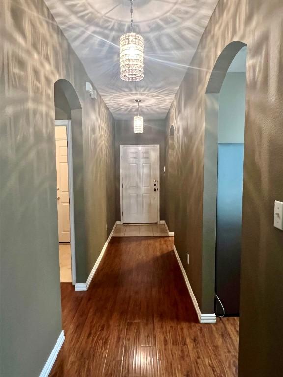 hall with arched walkways, wood finished floors, and baseboards