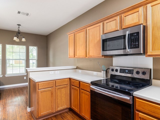 116 Brown St, Hutto, TX 78634 - kitchen featuring stainless steel appliances, a peninsula, a chandelier, dark wood-style floors, and light countertops