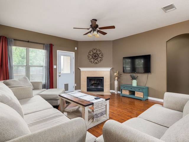 116 Brown St, Hutto, TX 78634 - living room with arched walkways, a ceiling fan, a tiled fireplace, wood finished floors, and baseboards