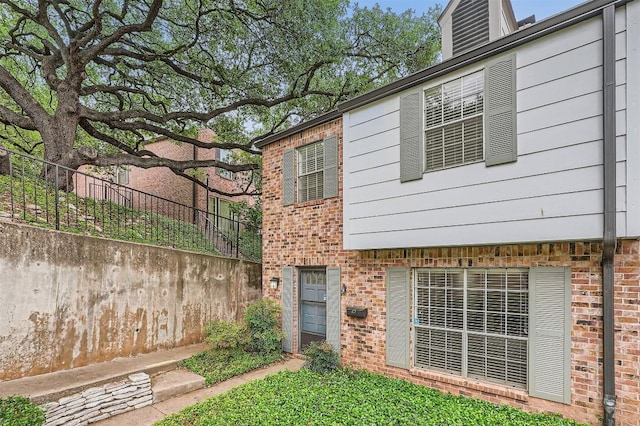 rear view of property featuring brick siding and fence