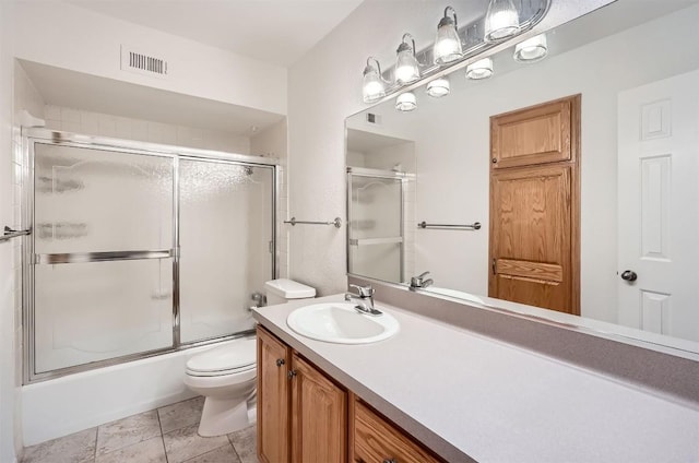 bathroom featuring visible vents, combined bath / shower with glass door, vanity, and toilet