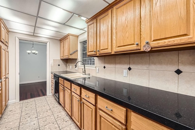kitchen with an inviting chandelier, dishwasher, a sink, baseboards, and tasteful backsplash