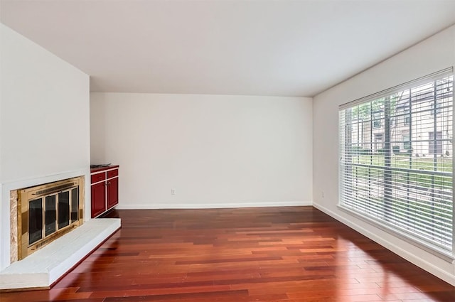 unfurnished living room with baseboards, a glass covered fireplace, and wood finished floors