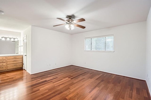 unfurnished bedroom featuring connected bathroom, ceiling fan, baseboards, and wood finished floors