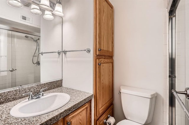 bathroom with visible vents, vanity, a tile shower, and toilet