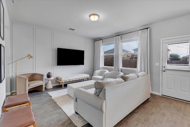 living area with plenty of natural light, visible vents, and light wood-style flooring