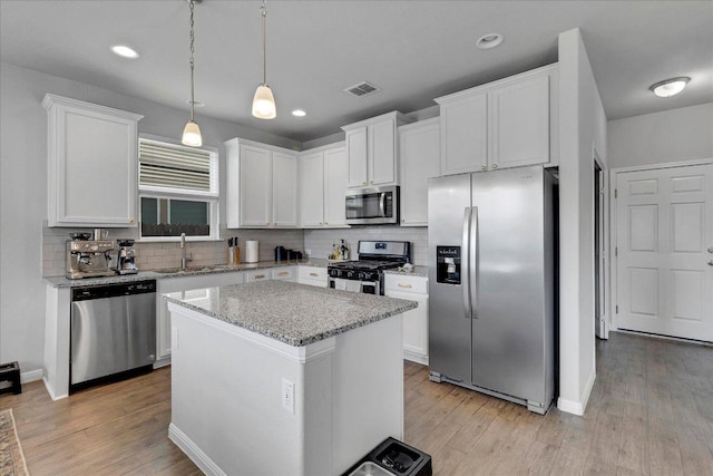 kitchen with backsplash, appliances with stainless steel finishes, a sink, and visible vents