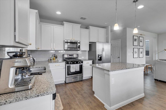 kitchen featuring backsplash, wood finished floors, a kitchen island, and stainless steel appliances