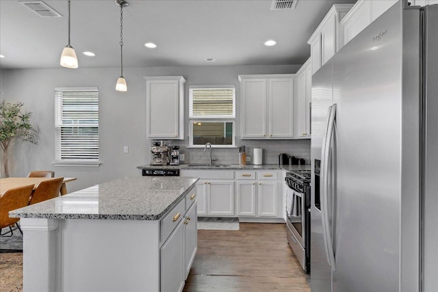 kitchen featuring tasteful backsplash, a sink, white cabinets, appliances with stainless steel finishes, and visible vents