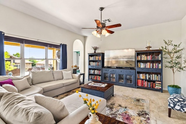 living room featuring arched walkways, visible vents, a ceiling fan, and baseboards