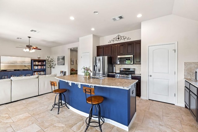 kitchen with stainless steel appliances, open floor plan, visible vents, decorative backsplash, and a breakfast bar area