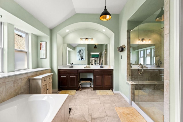 bathroom with a bath, vaulted ceiling, a healthy amount of sunlight, and a sink