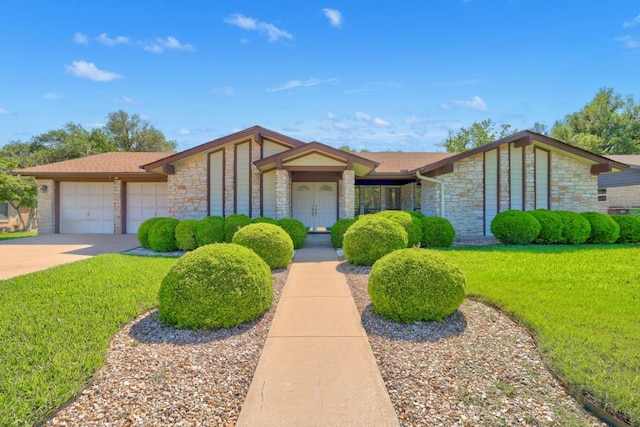 mid-century modern home with stone siding, concrete driveway, a front yard, and a garage