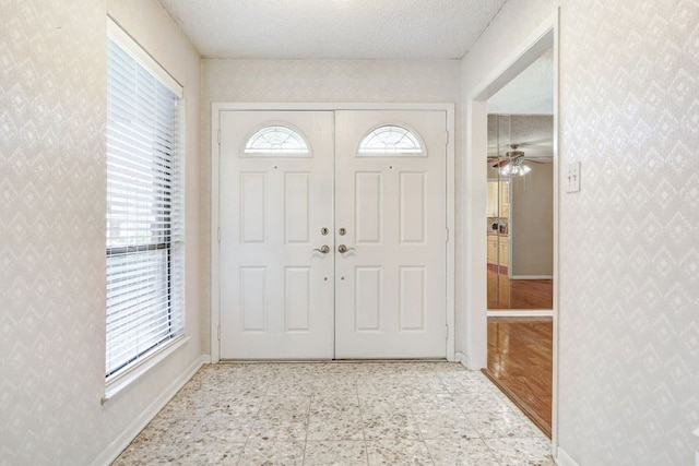 foyer with wallpapered walls, tile patterned floors, baseboards, and a ceiling fan
