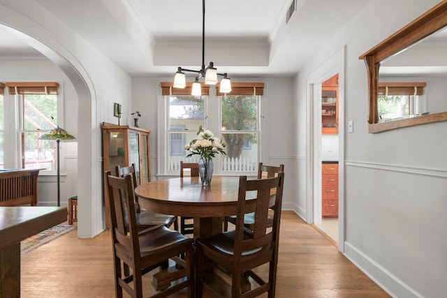 4103 Ave F, Austin, TX 78751 - dining room with crown molding, arched walkways, a raised ceiling, light wood-type flooring, and healthy amount of natural light