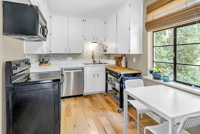 kitchen featuring light wood finished floors, light countertops, a sink, black electric range, and dishwasher