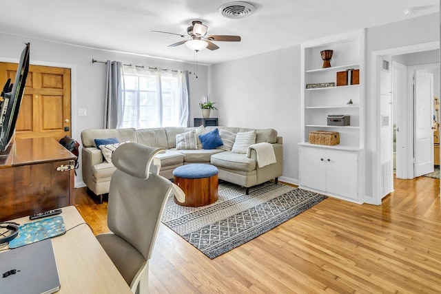 living room featuring light wood-style floors, visible vents, and a ceiling fan