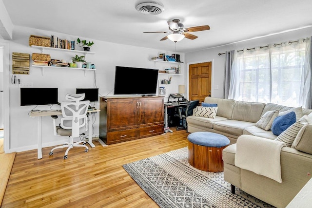 living room featuring baseboards, light wood-style flooring, visible vents, and ceiling fan