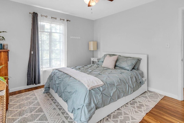 bedroom featuring wood finished floors, baseboards, and ceiling fan
