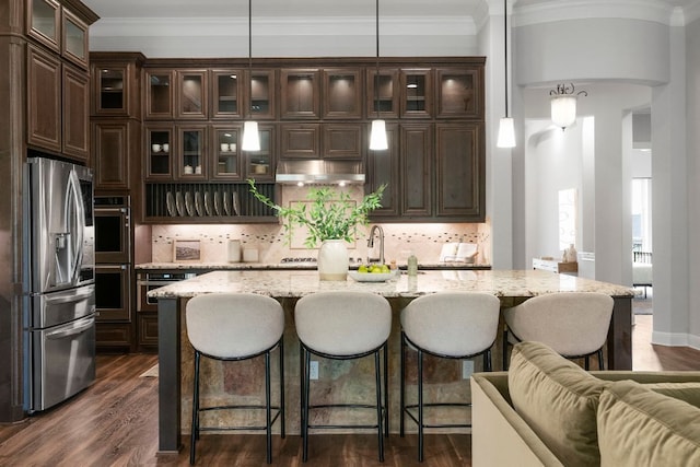 2304 High Lonesome, Leander, TX 78641 - kitchen with appliances with stainless steel finishes, dark brown cabinets, a kitchen breakfast bar, tasteful backsplash, and ornamental molding
