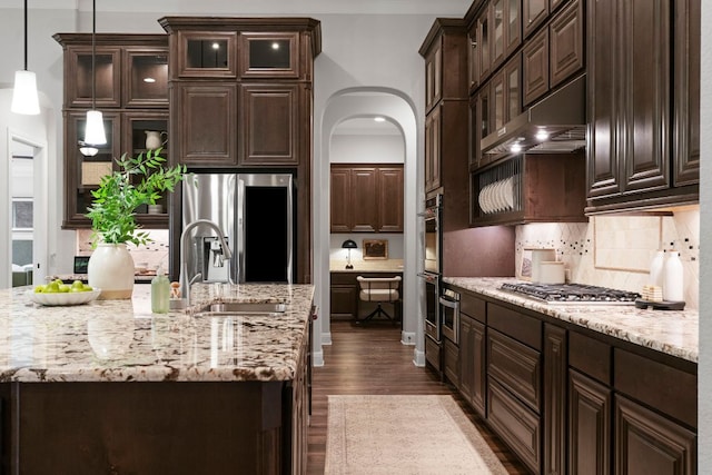 2304 High Lonesome, Leander, TX 78641 - kitchen featuring stainless steel appliances, under cabinet range hood, dark wood-type flooring, decorative backsplash, and dark brown cabinets