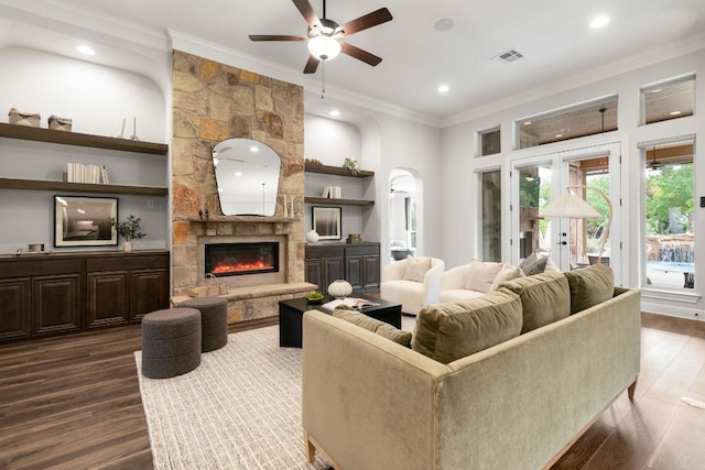 2304 High Lonesome, Leander, TX 78641 - living room with a ceiling fan, ornamental molding, dark wood-style flooring, a stone fireplace, and arched walkways