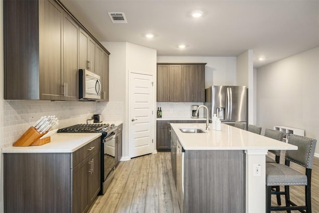 10310 Mager Ln, Hutto, TX 78634 - kitchen with appliances with stainless steel finishes, a sink, a kitchen breakfast bar, light wood-type flooring, and a kitchen island with sink