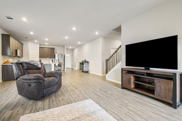 10310 Mager Ln, Hutto, TX 78634 - living room featuring light wood-type flooring, stairway, baseboards, and recessed lighting