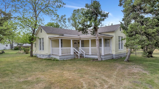bungalow with a shingled roof, a front lawn, and covered porch