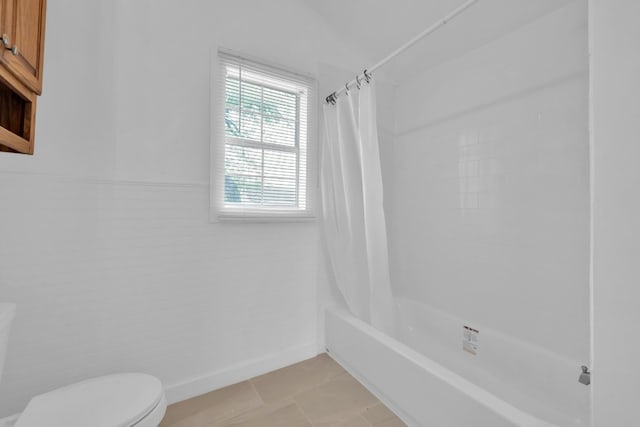bathroom featuring toilet, a wainscoted wall, and shower / tub combo with curtain