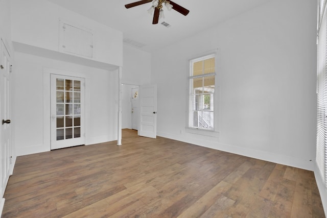 interior space with visible vents, a towering ceiling, a ceiling fan, and wood finished floors
