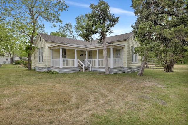 bungalow-style home featuring roof with shingles, a front yard, and covered porch