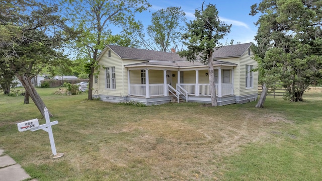 bungalow-style house featuring a chimney, a front lawn, a shingled roof, and covered porch