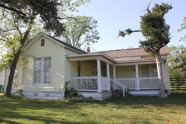 view of front of property featuring a front lawn, fence, a porch, and a shingled roof