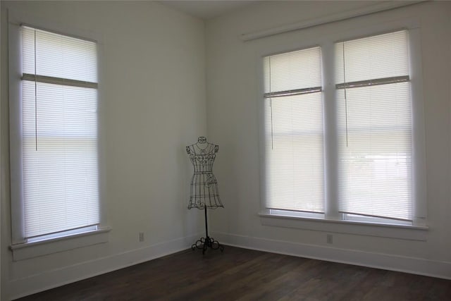 unfurnished room featuring baseboards and dark wood-style floors