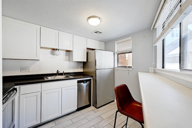 2500 Burleson Rd Unit 311, Austin, TX 78741 - kitchen featuring appliances with stainless steel finishes, a sink, dark countertops, and white cabinets