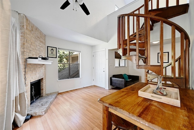 2500 Burleson Rd Unit 311, Austin, TX 78741 - living room featuring stairs, ceiling fan, wood finished floors, a brick fireplace, and vaulted ceiling