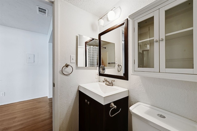 2500 Burleson Rd Unit 311, Austin, TX 78741 - bathroom featuring a textured wall, wood finished floors, vanity, a textured ceiling, and toilet