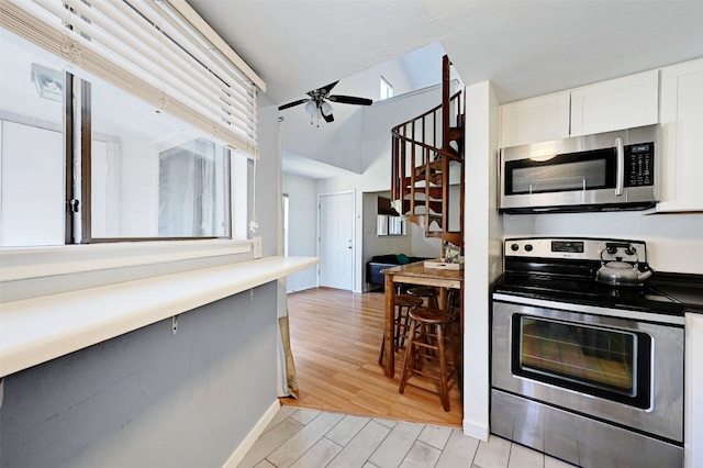 2500 Burleson Rd Unit 311, Austin, TX 78741 - kitchen featuring stainless steel appliances, a ceiling fan, light wood-style floors, white cabinetry, and high vaulted ceiling