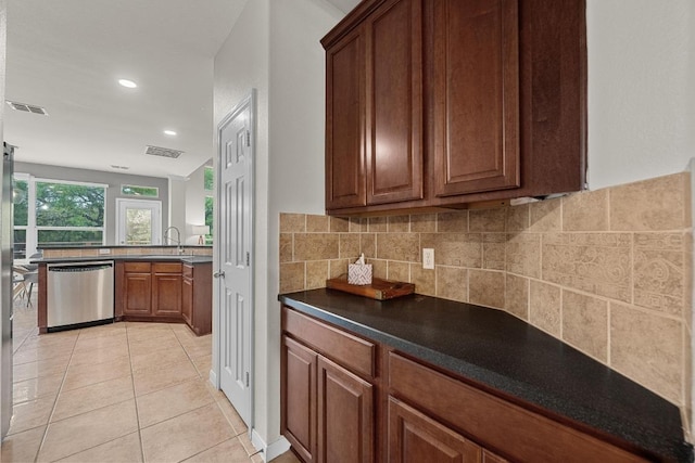 kitchen featuring dark countertops, visible vents, backsplash, dishwasher, and light tile patterned floors