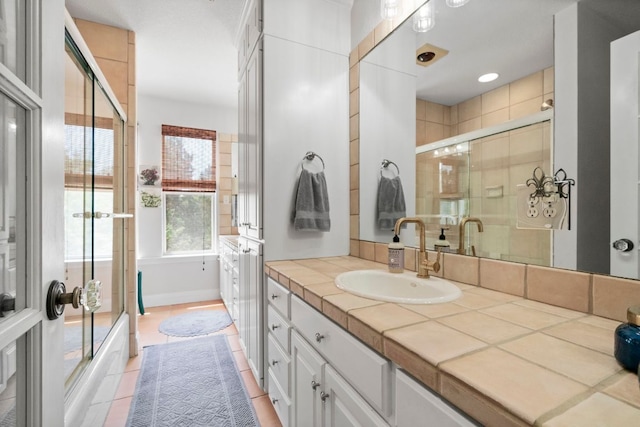 bathroom with tile patterned flooring, vanity, and bath / shower combo with glass door