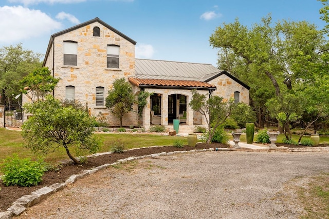 view of front of home featuring covered porch, stone siding, and fence