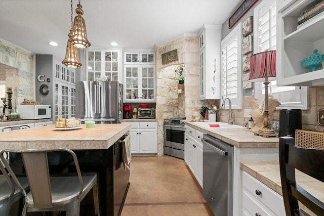 10921 Long Branch Dr, Austin, TX 78736 - kitchen with stainless steel appliances, tasteful backsplash, a sink, a breakfast bar, and concrete floors
