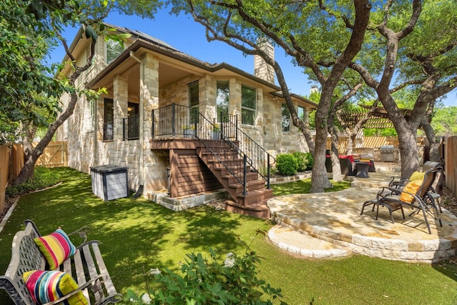 view of front of house featuring stone siding, a chimney, a patio, and stairs