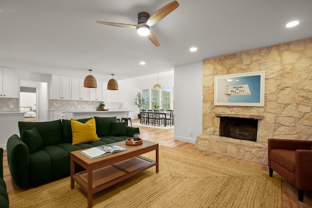 living room featuring a fireplace, a ceiling fan, light wood finished floors, and recessed lighting