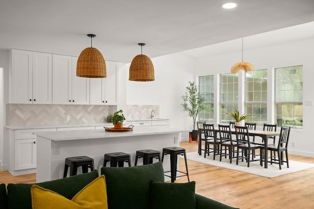 kitchen with white cabinets, light countertops, light wood finished floors, and tasteful backsplash