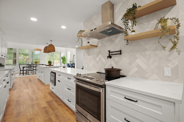 kitchen featuring ventilation hood, built in microwave, stainless steel range with electric cooktop, decorative backsplash, and open shelves