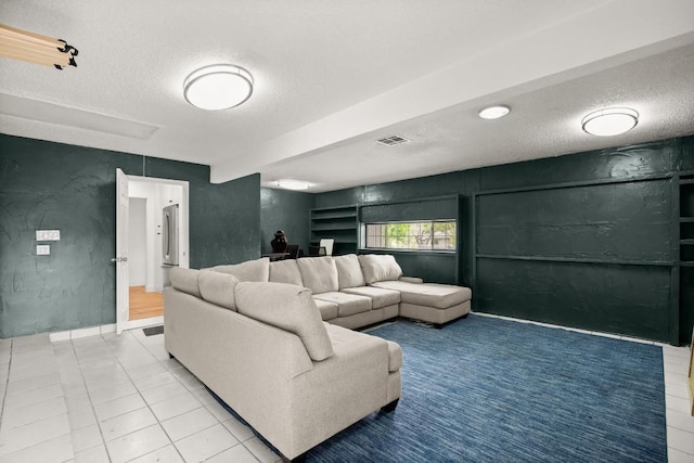 tiled living room featuring baseboards, visible vents, and a textured ceiling