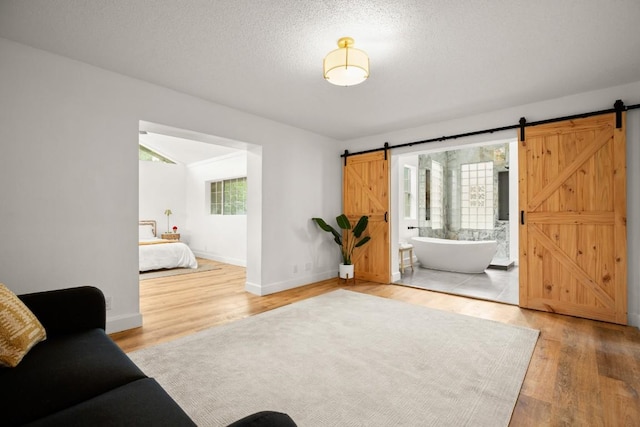 living room featuring a barn door, baseboards, and light wood finished floors